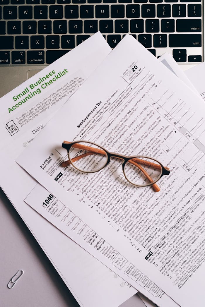 Services Overhead view of tax documents and eyeglasses on a laptop keyboard, ideal for finance or accounting themes.